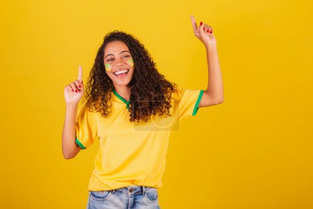 Photo for Young black Brazilian woman, soccer fan. dancing with raised fingers - Royalty Free Image
