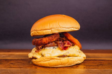 Téléchargez les photos : Délicieux burger de poulet au fromage mozzarella, bacon frit et rondelles d'oignon frit. - en image libre de droit