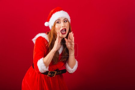 Foto de Hermosa brasileña pelirroja, vestida con ropa de Navidad, Santa Claus. gritando promoción. - Imagen libre de derechos