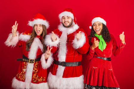 Photo for Brazilian friends, with christmas clothes, santa claus. sign of peace and love. - Royalty Free Image