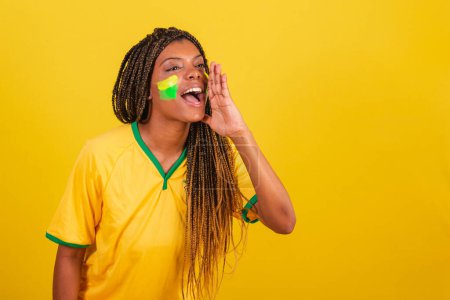 Foto de Mujer negra joven aficionada al fútbol brasileño. promoción gritando, llamando a la promoción. - Imagen libre de derechos