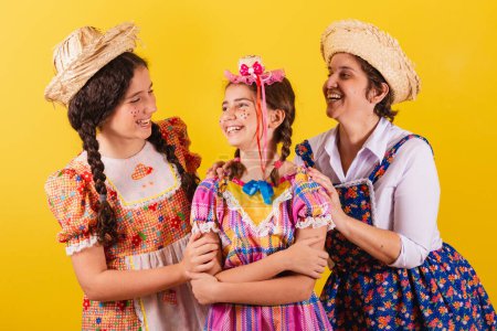 Foto de Abuela y sus dos nietas vestidas con ropa típica de Festa Junina. Abrazando y sonriendo. - Imagen libre de derechos