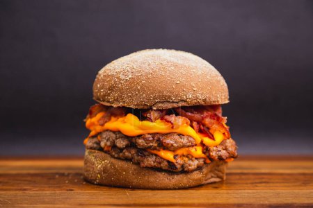 Foto de Deliciosa hamburguesa doble de ternera con queso cheddar y tocino frito. hamburguesa de carne, pan australiano - Imagen libre de derechos