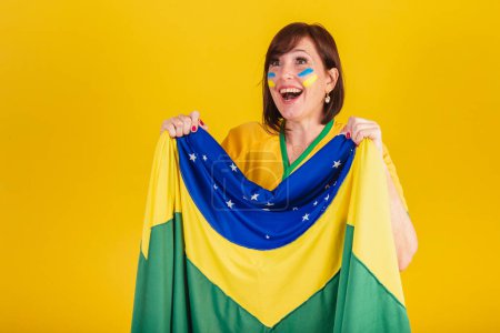 Photo for Red-haired woman, Brazilian soccer fan. fluttering with brazil flag, cheering and celebrating. - Royalty Free Image