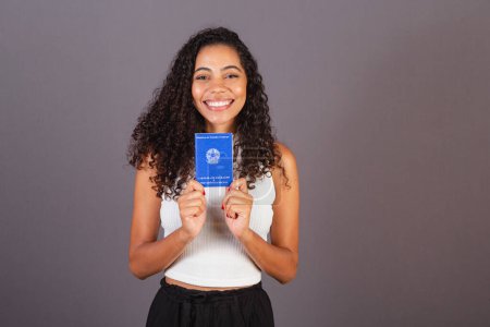 Foto de Joven brasileña negra sosteniendo billetera de trabajo. CLT, Tarjeta de Trabajo y Seguridad Social - Imagen libre de derechos