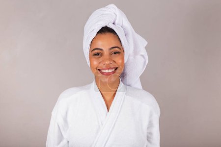 Téléchargez les photos : Belle femme noire brésilienne, portant peignoir et serviette. Gros plan photo, sourire, dents, bien-être. - en image libre de droit
