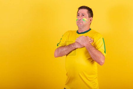 Photo for Adult man, soccer fan from Brazil, hands on chest singing national anthem. - Royalty Free Image