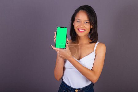 Photo for Young adult woman from northeastern brazil. holding smartphone, chroma key screen, apps, app, technology, mobile. - Royalty Free Image