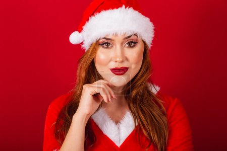 Foto de Hermosa brasileña pelirroja, vestida con ropa de Navidad, Santa Claus. primer plano de la cara de la modelo. - Imagen libre de derechos