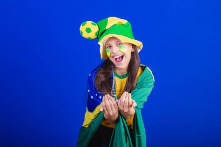 Photo for Young girl, soccer fan from Brazil. dressed in hat and flag. calling with your hands. - Royalty Free Image