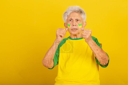 Téléchargez les photos : Femme âgée, fan de football du Brésil, acclamant et vibrant. - en image libre de droit