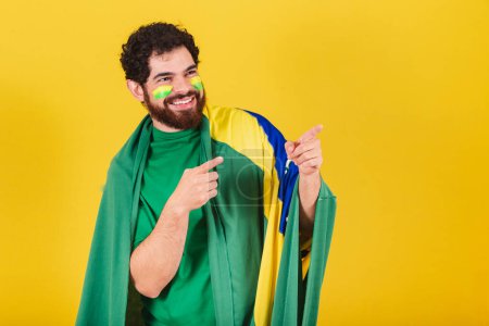 Photo for Man, brazilian, bearded, soccer fan from brazil, pointing to something in the distance, showing something, indicating. Advertising photo. - Royalty Free Image