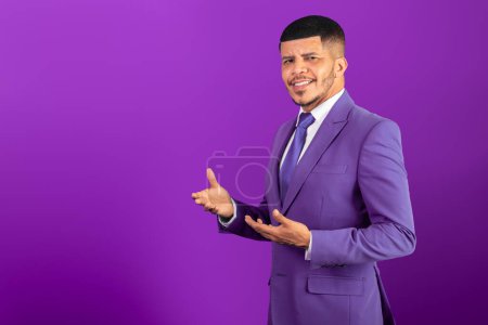 Foto de Hombre negro brasileño, vestido con traje y corbata púrpura. Violet, hombre de negocios. presentar algo a la izquierda - Imagen libre de derechos