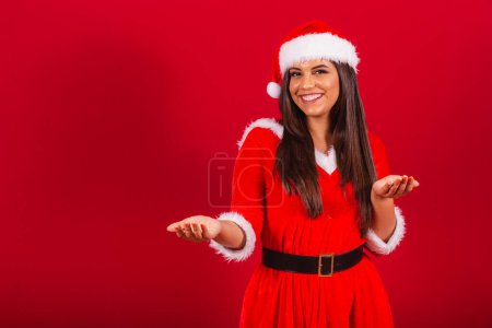 Téléchargez les photos : Belle Brésilienne vêtue de vêtements de Noël, le Père Noël. invitant les mains. - en image libre de droit