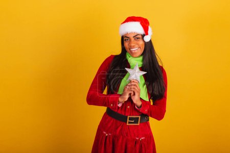 Photo for Beautiful black Brazilian woman, dressed in christmas clothes, santa claus, holding christmas star. - Royalty Free Image