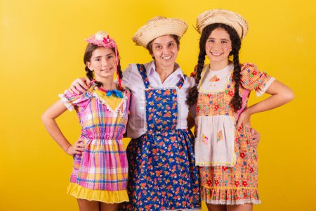 Photo for Grandmother and her two granddaughters dressed in typical Festa Junina clothes. Hugging and smiling. - Royalty Free Image