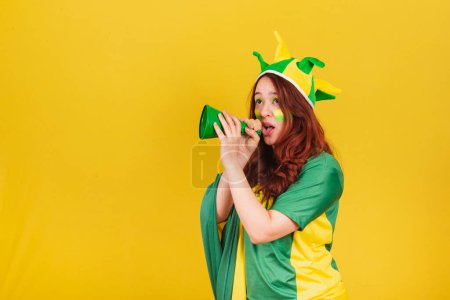 Photo for Caucasian redhead woman brazil soccer fan screaming promotion using mega phone, publicity photo. - Royalty Free Image