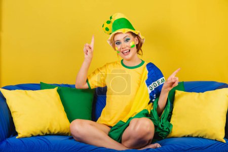 Foto de Mujer caucásica, pelirroja, fan del fútbol brasileño, brasileña, en el sofá bailando - Imagen libre de derechos