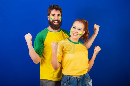 Photo for Caucasian couple, brazil soccer fans, holding arms in celebration - Royalty Free Image