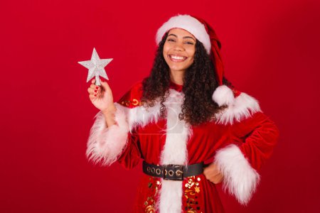 Photo for Beautiful brazilian black woman, dressed as santa claus, christmas clothes. holding christmas star, decoration. - Royalty Free Image