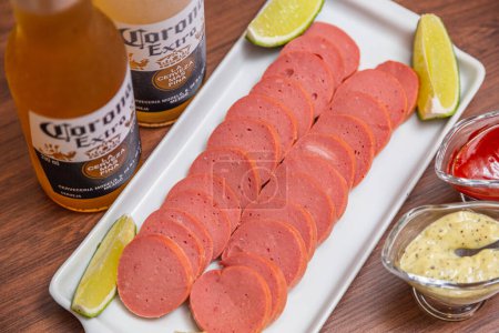 Photo for Cambu chicken and sausage croquette, typical Brazilian snack, served with lemon slices, chili sauce and mayonnaise On the wooden table served with the famous corona beer. - Royalty Free Image