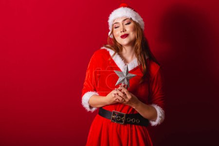 Téléchargez les photos : Belle femme rousse brésilienne, vêtue de vêtements de Noël, le Père Noël. tenant étoile de Noël. - en image libre de droit
