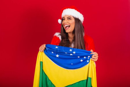 Photo for Beautiful Brazilian woman dressed in Christmas clothes, Santa Claus. with brazil flag. - Royalty Free Image