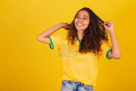 Foto de Joven brasileña negra, fanática del fútbol. bailando, jugando con su pelo. - Imagen libre de derechos