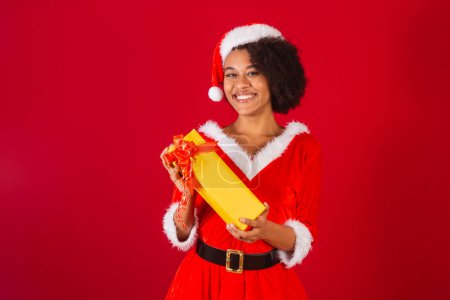 Photo for Beautiful black brazilian woman, dressed as santa claus, mama claus, happy holding present - Royalty Free Image