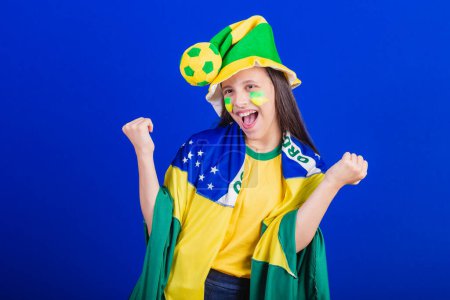 Photo for Young girl, soccer fan from Brazil. dressed in hat and flag. celebrating - Royalty Free Image