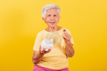 Foto de Anciana sosteniendo moneda y alcancía, concepto de jubilación, finanzas y economía. - Imagen libre de derechos
