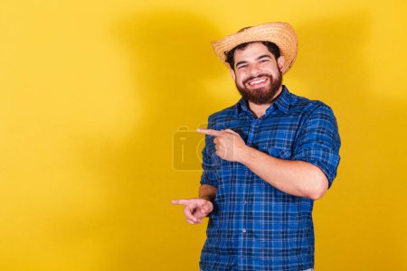 Photo for Bearded man, wearing typical clothes for the Festa Junina. Feast of Arrai de So Joo. Pointed to the side, negative space for text or advertising - Royalty Free Image