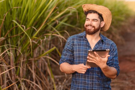 Photo for Brazilian caucasian man, farmer, rural worker, agricultural engineer, holding tablet and looking at the sky. Agriculture and technology. - Royalty Free Image