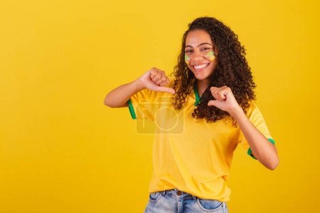 Photo for Young black Brazilian woman, soccer fan. pointing at herself, choosing herself. I got it. - Royalty Free Image