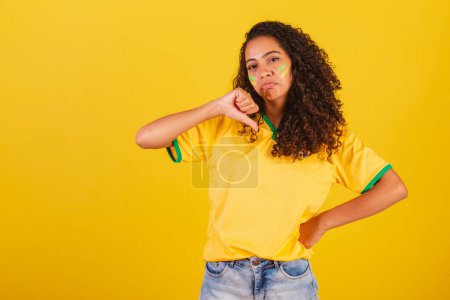 Foto de Joven brasileña negra, fanática del fútbol. signo de aversión, pulgar hacia abajo, desaprobación, malo. - Imagen libre de derechos
