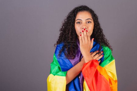 Foto de Joven brasileña negra, cubriéndose la boca, militancia con bandera LGBT, diversidad, lucha contra los prejuicios. - Imagen libre de derechos