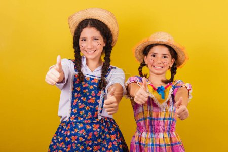Photo for Sisters and friends, wearing typical clothes of the Festa Junina. Thumb up. Positive, affirmative. Approval. - Royalty Free Image