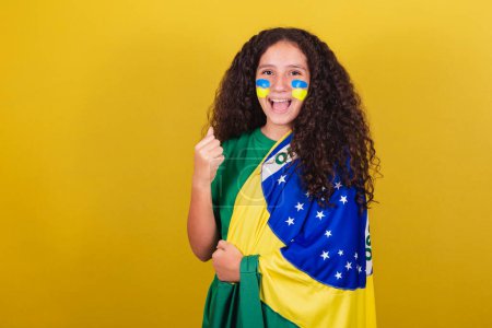 Foto de Chica brasileña caucásica, fanática del fútbol, puño cerrado, gritando sí, celebrando la victoria de Brasil. - Imagen libre de derechos
