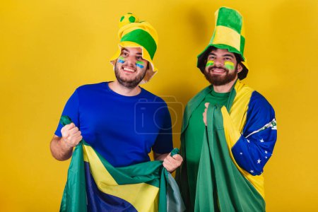 Foto de Dos amigos, brasileños, aficionados al fútbol de Brasil, vestidos para animar en un campeonato. - Imagen libre de derechos