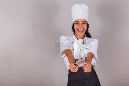 Photo for Young black Brazilian woman, cook. Holding knife and fork for preparing meat, barbecue. - Royalty Free Image
