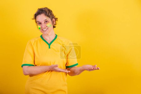 Téléchargez les photos : Adulte femme adulte, fan de football brésilien, présentant quelque chose à droite, photo de publicité. - en image libre de droit