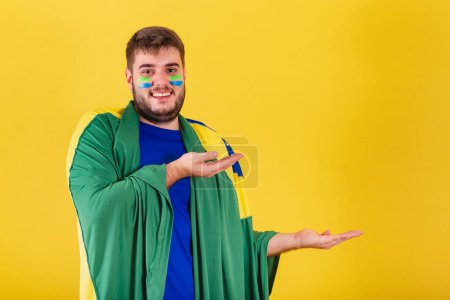 Photo for Brazilian caucasian man, soccer fan from brazil, pointing hands some product to the right, photo for ad. indicating. - Royalty Free Image