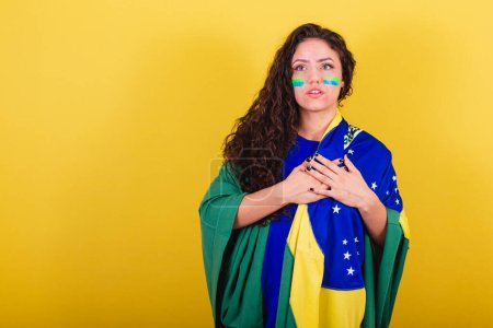 Photo for Woman soccer fan, fan of Brazil, World Cup, singing the national anthem. hand on chest. - Royalty Free Image
