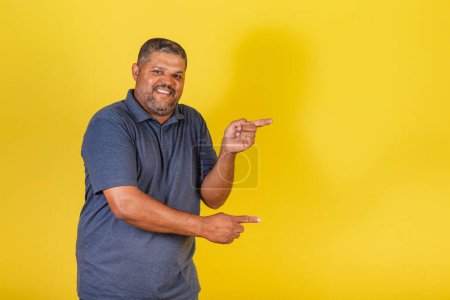Foto de Hombre negro brasileño, adulto sonriendo, señalando a la derecha, foto publicitaria - Imagen libre de derechos