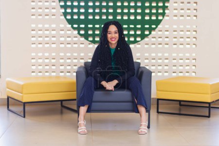 Photo for Young black woman, brazilian, entrepreneur, business woman, smiling optimist. Sitting in an armchair. - Royalty Free Image