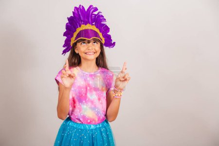 Photo for Beautiful Brazilian girl, child, dressed for carnival in Brazil. cheering hard, wishing, lucky sign. - Royalty Free Image