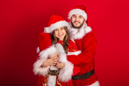 Téléchargez les photos : Couple brésilien avec vêtements de Noël, Père Noël claus. embrassé romantiquement. - en image libre de droit