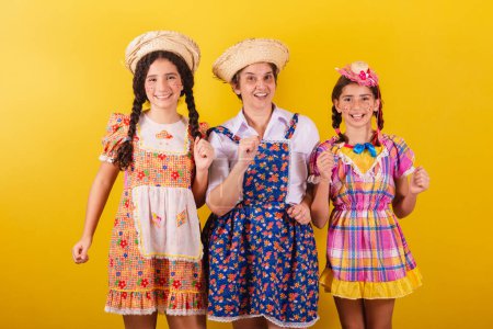Téléchargez les photos : Grand-mère et ses deux petites-filles vêtues de vêtements typiques de Festa Junina. Danse, fête, fête. - en image libre de droit