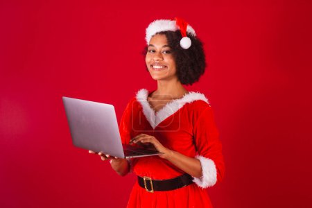 Téléchargez les photos : Belle femme brésilienne noire, habillée en Père Noël, maman Claude, tenant un carnet - en image libre de droit