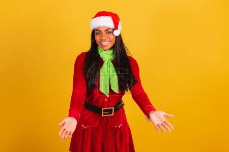 Photo for Beautiful black Brazilian woman, dressed in Christmas clothes, Santa Claus, with open arms, welcome. - Royalty Free Image